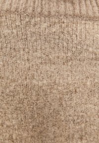 Close-up of beige wool fabric with a textured, looped knit pattern.