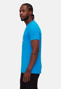 Blauw T-shirt met korte mouwen, gemaakt van katoen. Ronde hals ontwerp, soepele textuur, met een witte afbeelding aan de voorkant. De pasvorm is ontspannen.