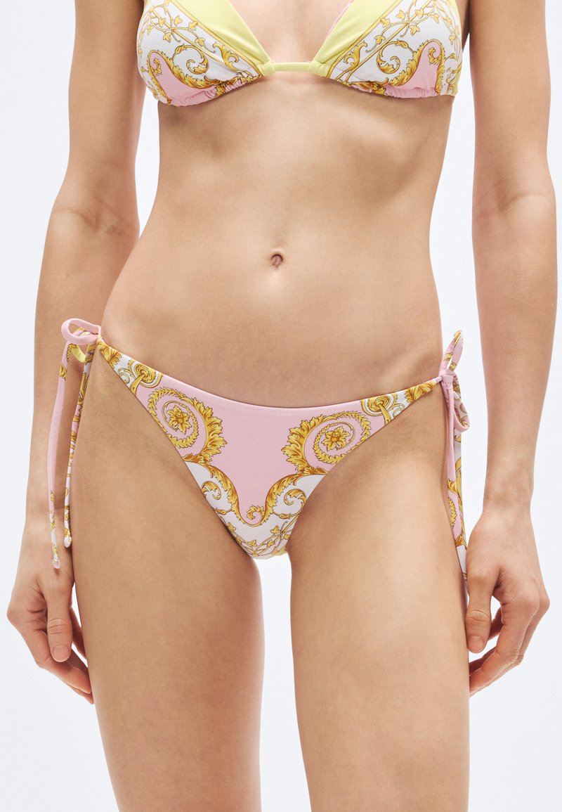 Bikini set v ružovej a pastelovo žltej farbe s dekoratívnym vzorom zlatých ornamentov. Nastaviteľné bočné šnúrky na nohavičkách bikin. Mäkk�á textúra látky.