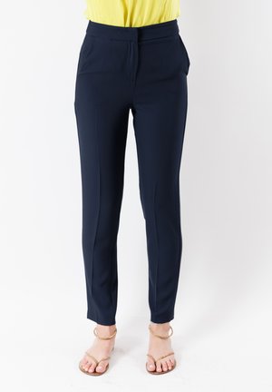 Pantaloni tapered navy con una texture liscia, dotati di tasche frontali, vita piatta e pieghe nette lungo le gambe.