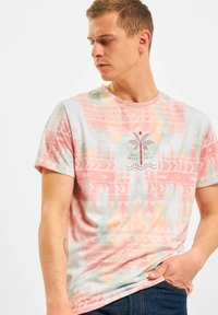 Short-sleeve t-shirt in pastel colors with abstract patterns and a palm tree graphic on the front. Cotton texture, crew neck design.
