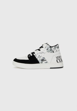 Wysokie sneakersy w czarno-białej skórze i zamszu, z floralnym wzorem, czarnymi sznurówkami i napisem "VERSACE COUTURE" na pięcie.