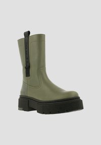 Olijfgroene waterdichte enkelboot met een dikke zwarte zool, ronde neus en een trekband aan de zijkant; gladde afwerking met stiksels.
