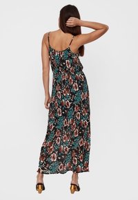 Maximekkimekko, jossa on musta kukkakuosi, ohuet olkaimet, istuva vyötärö ja valuva helma. Tekstuuroitu kangas värikkäillä yksityiskohdilla.