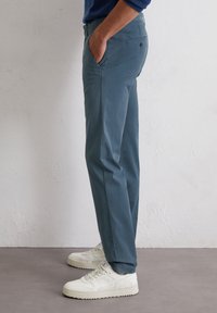 Heren blauwe chino broek van lichtgewicht stof met een rechte broekspijpen ontwerp, zijzakken en een achterzak met een knoopdetail.