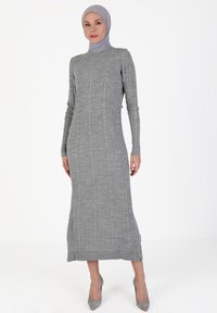 Gray ribbed dress with long sleeves and a high neckline, featuring a fitted silhouette and side slits at the hem, made of soft knit fabric.
