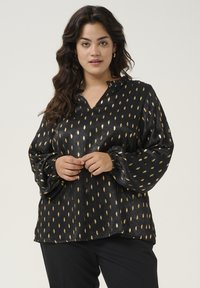 Black blouse with a V-neck and ruffled collar, featuring a gold leaf pattern, long puffed sleeves with elastic cuffs, and a smooth texture.