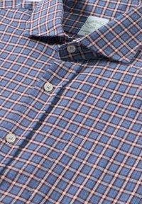 Camicia a quadri blu e rossa con bottoni bianchi e colletto, dotata di taschino sul petto e di un'etichetta del marchio visibile all'interno del colletto.