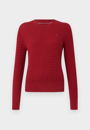 Red knitted sweater with a textured, cable pattern. Long sleeves, round neckline, and a fitted hem. Small logo on the chest.