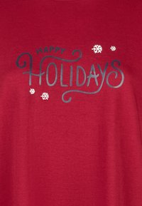 Rood stof met de tekst 'Happy Holidays' in grote decoratieve letters en witte sneeuwvlokken rondom de tekst.