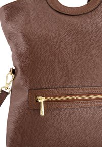 Braune Ledertasche mit strukturierter Oberfläche, ausgestattet mit einem oberen Griff und einer goldfarbenen Reißverschlusstasche auf der Vorderseite.