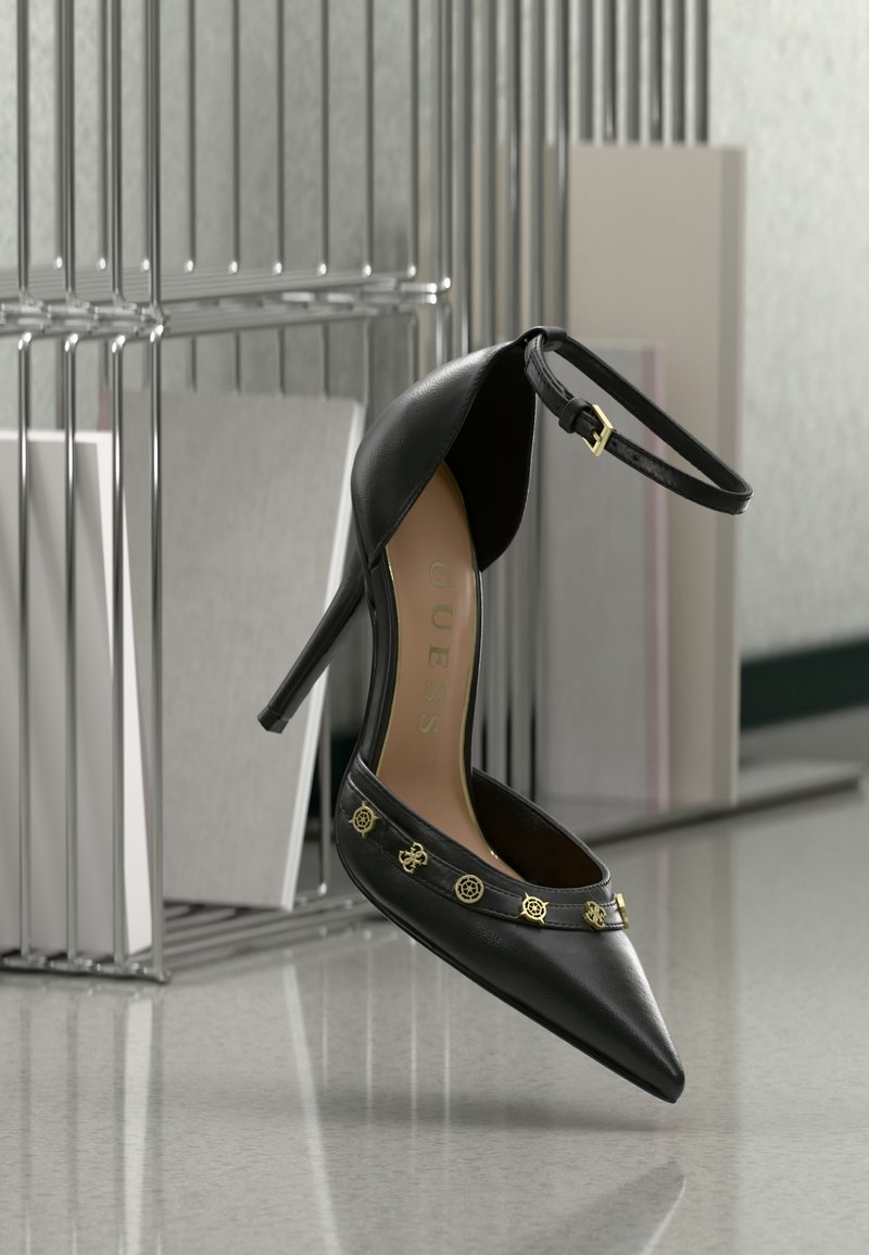 Crna kožna ženska cipela s visokim potpeticama i špicastim vrhom, nježni zlatni detalji na remenu i podesivi remen oko gležnja. Glatka tekstura, elegantan dizajn.