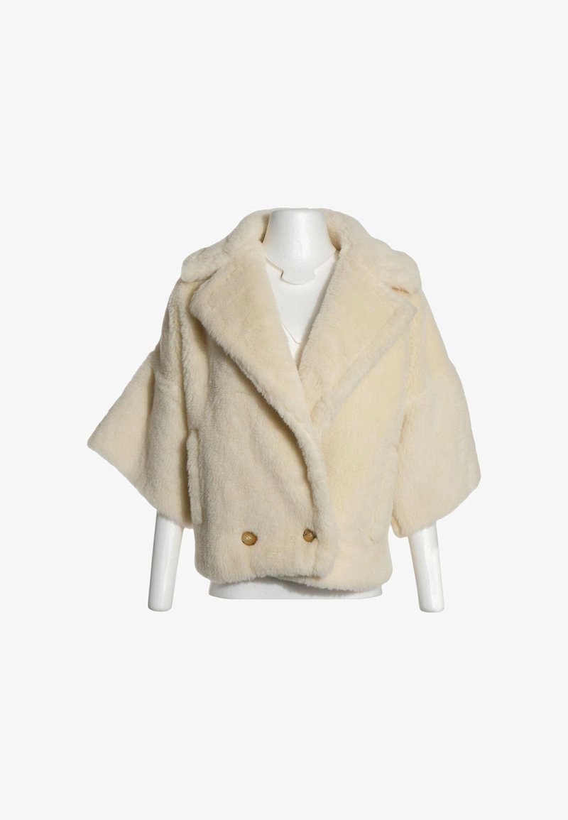 Veste courte en fausse fourrure crème avec larges revers, manches trois-quarts et deux boutons à l'avant sur un mannequin.