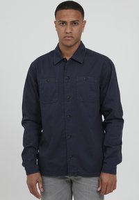 Camicia a maniche lunghe blu navy con bottoni, due tasche sul petto e colletto strutturato, realizzata in tessuto leggero.
