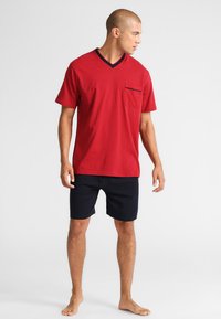 Rood T-shirt met korte mouwen en V-hals, voorzien van een zak en een klein patroon, gecombineerd met marineblauwe shorts. Van katoen, casual pasvorm.