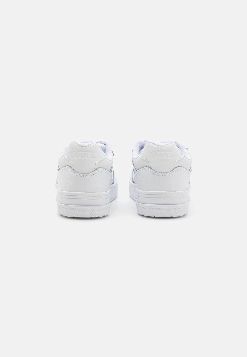 Baskets basses blanches en cuir texturé, avec des cols rembourrés et une semelle en caoutchouc lisse ; arbore le logo Vans en relief sur le talon.