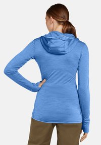 Sudadera de manga larga con capucha en azul claro, fabricada con un tejido texturizado, diseño ajustado y detalles de costura. Cuenta con un bolsillo tipo canguro en la cintura.