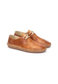 Zapatos de cuero marrón con punta redondeada, detalles cosidos alrededor de la suela y cordones en un tono beige claro. Textura suave, diseño casual.