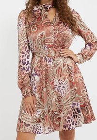 Robe à manches longues avec un motif cachemire et animalier dans des tons terreux. Elle comporte une taille ceinturée et un détail nœud au niveau de l'encolure.