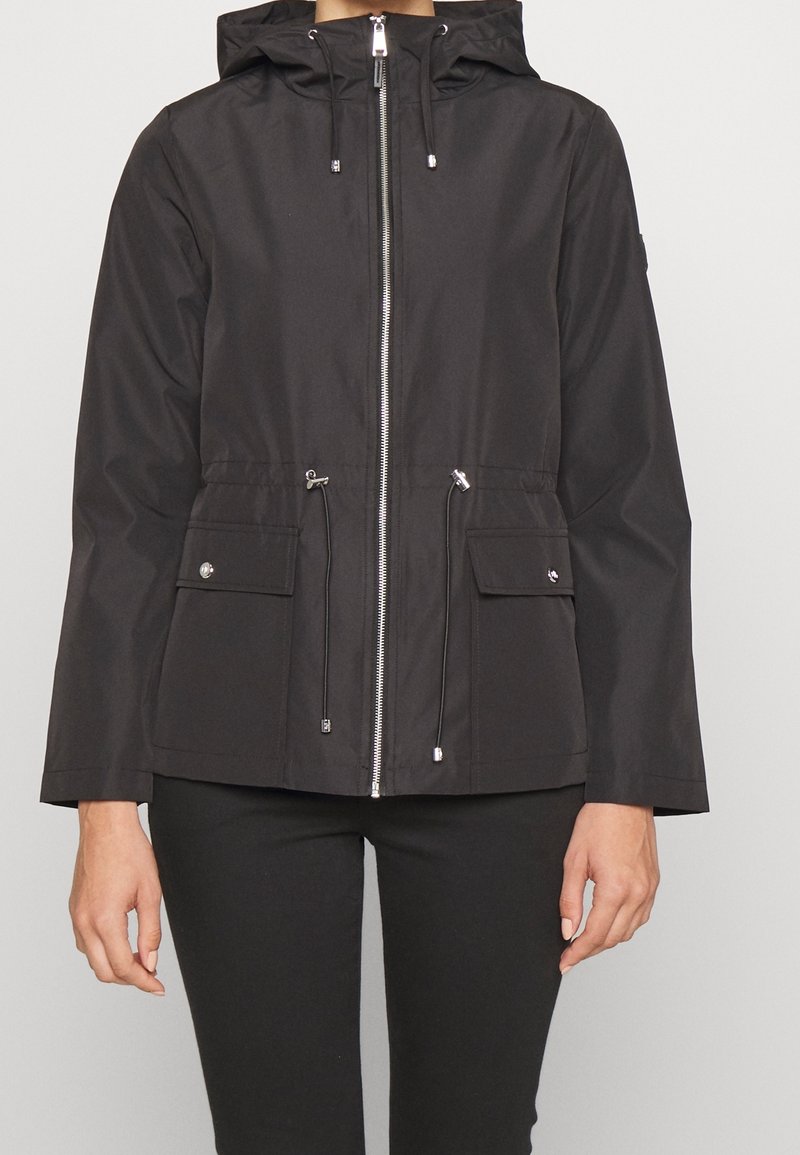 Czarna wodoodporna kurtka z kapturem, zapinana na zamek, z regulowanymi troczkami, dwoma przednimi kieszeniami i gładką fakturą. Odpowiednia na różne warunki pogodowe.