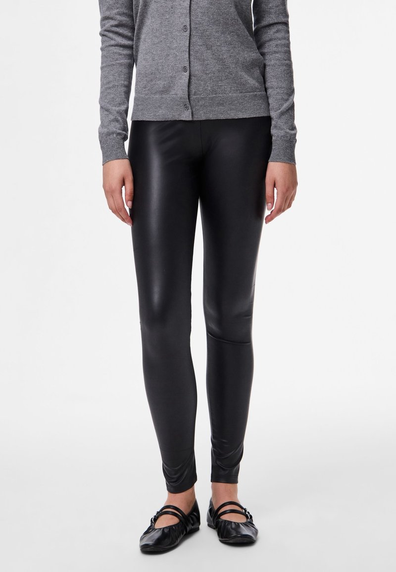 Black, high-shine leggings with a slim fit, made of stretchy material, paired with a gray button-up cardigan and black ballet flats.
