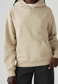 Felpa beige con cappuccio, tasca frontale, polsini e orlo a costine. Realizzata in tessuto morbido, presenta una vestibilità comoda e un design semplice.