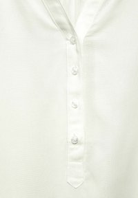 Camicia bianca di cotone con scollatura a V, cinque bottoni trasparenti e una texture liscia con una leggera lucentezza.