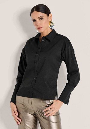 Zwarte button-up overhemd met een getailleerd ontwerp, voorzien van subtiele stippenpatronen. Lange mouwen en een klassieke kraag, gecombineerd met metallic broek.
