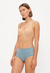 Nøgen underwire bh med justerbare stropper, parret med højtaljede blå trusser, glat stofstruktur og minimalistisk design.