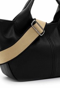 Sac en cuir noir avec surface texturée, doté d'une sangle en toile beige et de ferrures argentées. Forme arrondie avec des détails de couture visibles.