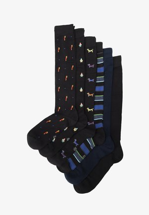 Set van zeven knielange zwarte sokken met verschillende patronen, waaronder kleurrijke pepers, feestelijke bomen en strepen. Gemaakt van zacht materiaal.