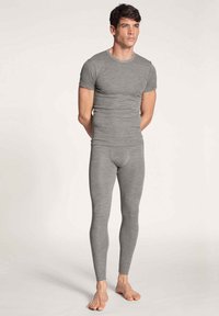 T-shirt grigio aderente e leggings realizzati in un morbido materiale elasticizzato. Il design è senza cuciture con una finitura pulita, adatto per l'abbigliamento sportivo.