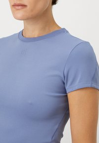Camisetta corta a maniche con righe di colore azzurro chiaro, con scollatura a girocollo, caratterizzata da un sottile dettaglio del logo in rilievo sul petto e spalle senza cuciture.