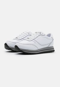 Chaussures de sport blanches avec une tige en cuir, des accents argentés et une semelle en caoutchouc noire. Modèle à bout arrondi et à lacets.