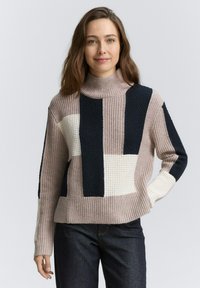 Pull en laine mélangée avec col roulé, présentant des motifs en blocs beiges, bleu marine et crème. Tricot texturé avec des poignets et un ourlet côtelés.