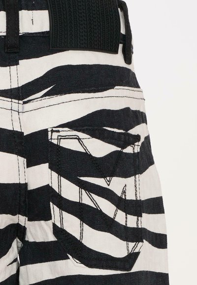 Zwart-wit gestreepte stofbroek met een gestructureerde zwarte tailleband en een opvallende zak met geometrische stiksels.