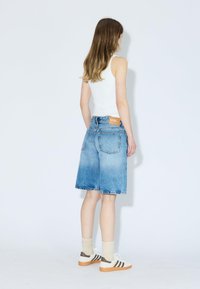 Shorts en denim de couleur bleue claire avec un effet dégradé, dotés d'une taille mi-haute, de jambes larges et d'une étiquette en cuir marron sur la ceinture arrière.