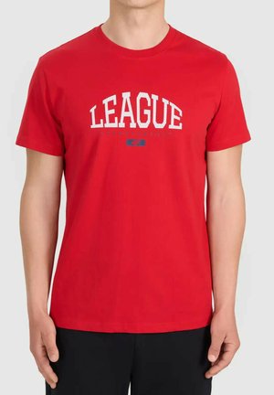 Osoba nosząca czerwoną koszulkę z krótkim rękawem z napisem "LEAGUE" białymi literami na piersi, w połączeniu z czarnymi spodniami.