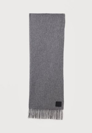 Écharpe en laine grise douce avec des extrémités à franges et une petite étiquette noire rectangulaire près d'un bord, étalée à plat sur un fond blanc.