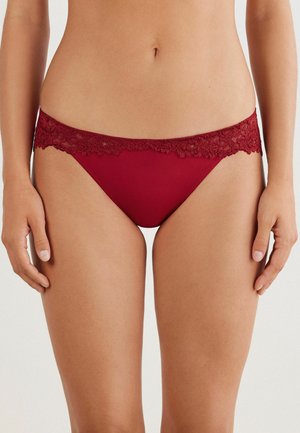 Burgunderfarbene Panties mit Spitzenbesatz, die einen glatten Körper, einen gewellten Rand und ein minimalistisches Design aufweisen, das Komfort und Passform betont.