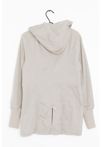 Beige huvad jacka med slät textur, resårmuddar och en knapplayout nära fållen. Baksidan har sömlinjer för en figurnära passform.