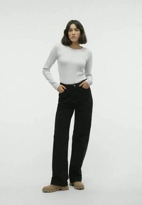 Gray long-sleeve top paired with black wide-leg pants and beige chunky shoes. The outfit features a simple design and neutral colors.