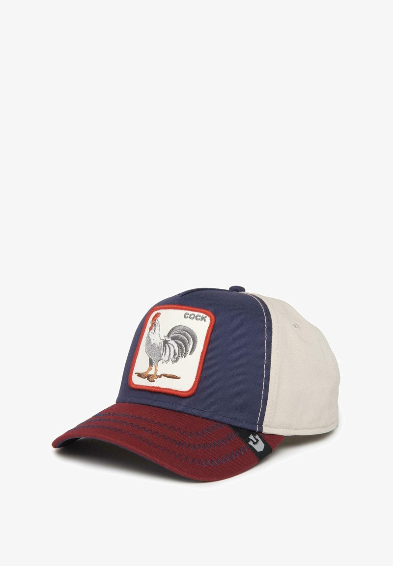 Gorra de béisbol con una parte frontal color azul marino y un parche de gallo, lados color crema y visera burdeos con detalles de costura en contraste.