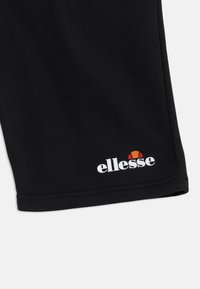 Čierne šortky vyrobené z bavlnenej zmesi, s logom "ellesse" v bielej farbe a farebným akcentom nad ním, a jednoduchým lemom.