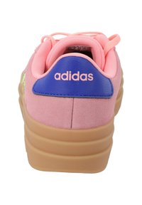 Różowe zamszowe sneakersy z niebieskim skórzanym akcentem na pięcie, z logo "adidas" i gumową podeszwą. O zaokrąglonym kształcie i z zapięciem na sznurowadła.