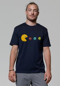 Navy-blaues T-Shirt aus Baumwolle mit einem gelben Pac-Man-Graphic und vier bunten Geistern in einer Reihe, die ausdrucksstarke Gesichtsdesigns aufweisen.
