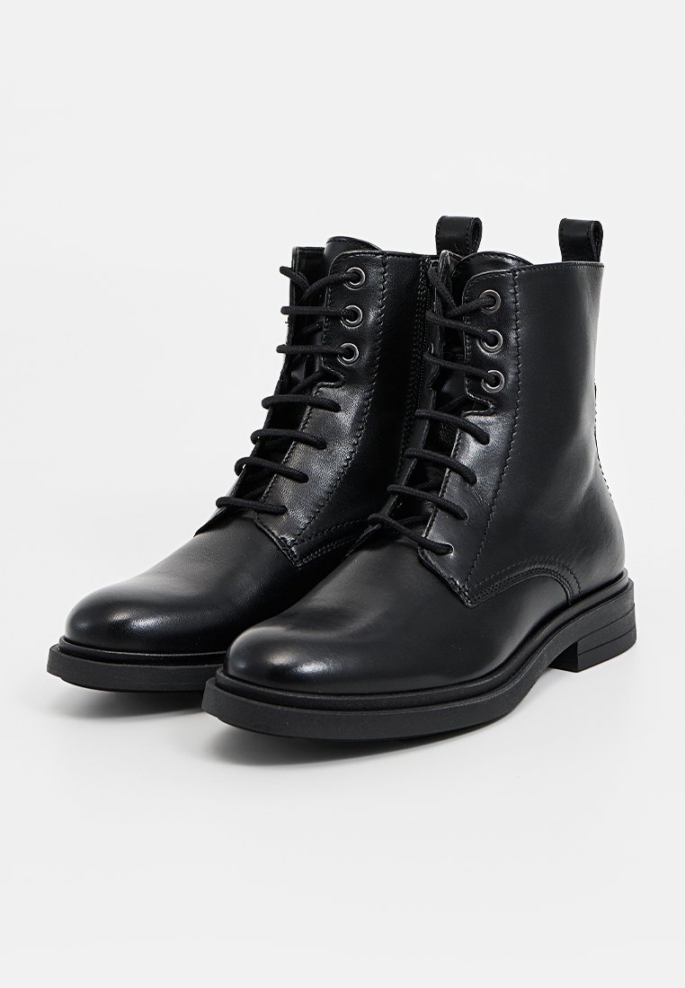 Schwarze Leder-Stiefeletten mit Schnürung, runder Zehenpartie, Gummisohle und genähten Details an den Seiten. Mit einer Zuglasche für einen einfachen Einstieg.
