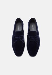 Loafers din catifea bleumarin, cu un design cusut, vârf rotunjit și un accent cu fundă în față. Textură netedă și stil slip-on.