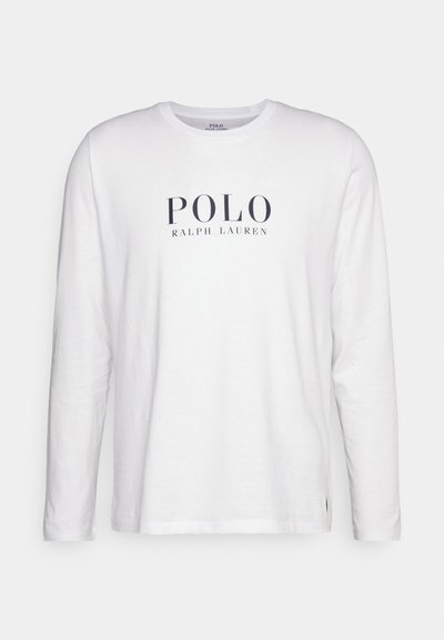 Garā piedurkņu balta kokvilnas t-kreklā ar tumši zilu "POLO RALPH LAUREN" logotipu centrā uz krūtīm, ar apļa kakla izgriezumu un brīvu piegriezumu.