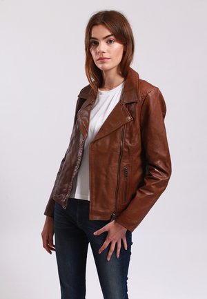 Brown leather biker jacket with a slightly textured finish, asymmetrical zipper, and snap collar detail; worn over a white shirt.